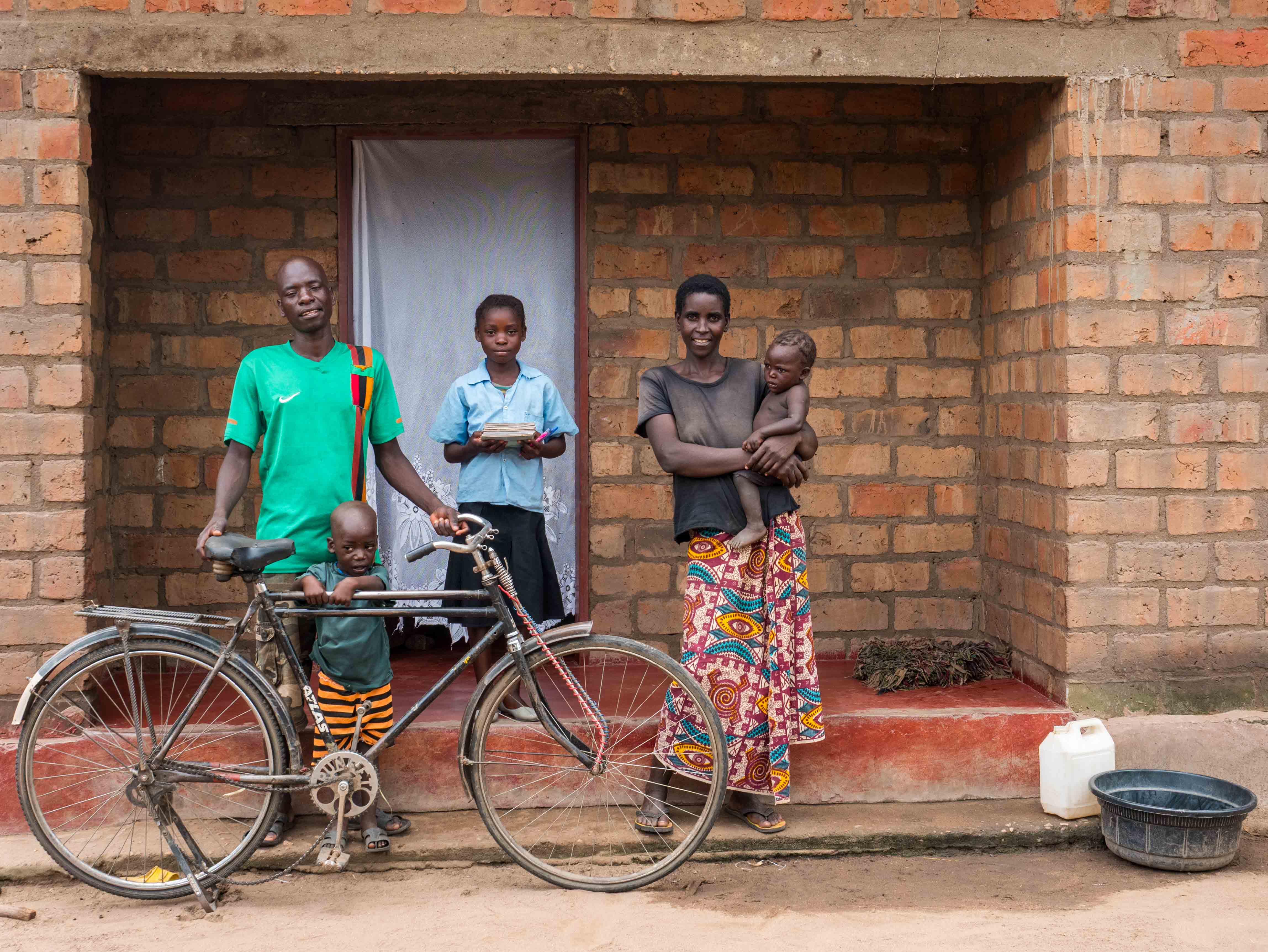 Family with bicycle outside their brick home