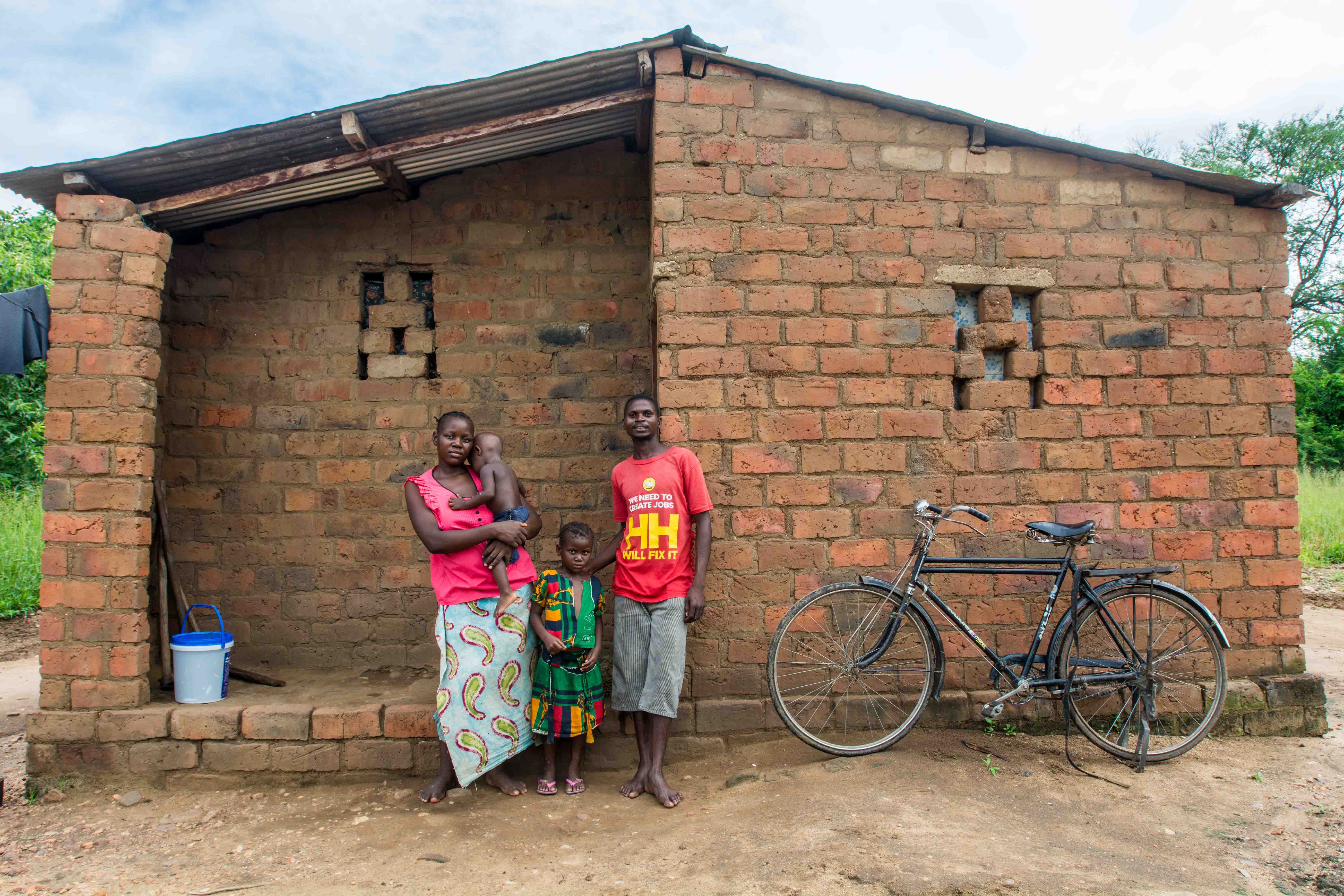 Family with bicycle outside their brick home